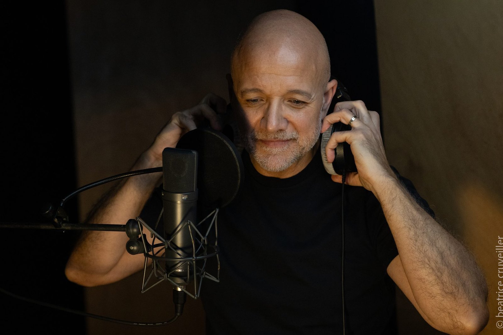 Alain Ghazal, casque aux mains, dans la lumière chaude du studio